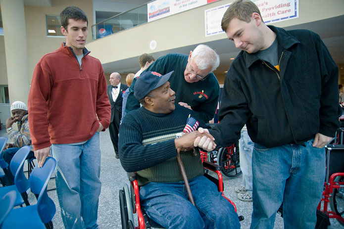 A Knight from Knights of Columbus shakes hands with a veteran in a new wheelchair
